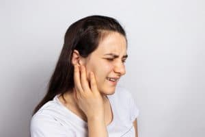 The woman has a sore ear - infection, inflammation from infection and otitis. Perforation ruptured the eardrum. Arthritis of the temporal lower jaw joint, osteoarthritis and pain in the jaw, mastoiditis.