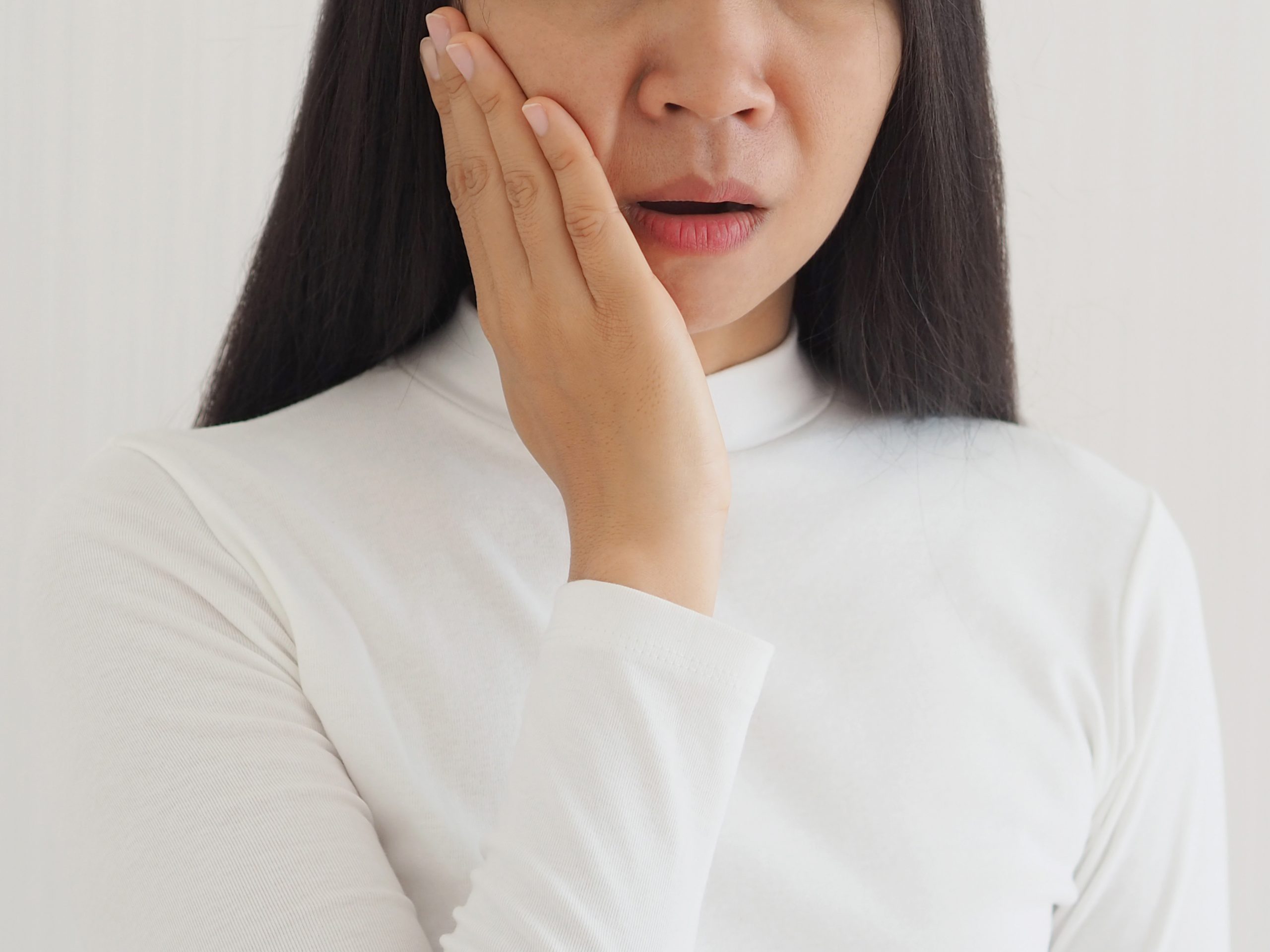 trigeminal neuralgia and temporomandibular joint and muscle disorder in asian woman, She use hand touching her cheek and symptoms fo pain and suffering on isoleted white background.