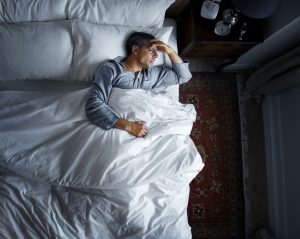 Man on bed with a headache