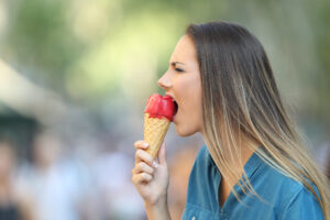 Side view portrait of a woman with hypersensitivity biting an ice cream