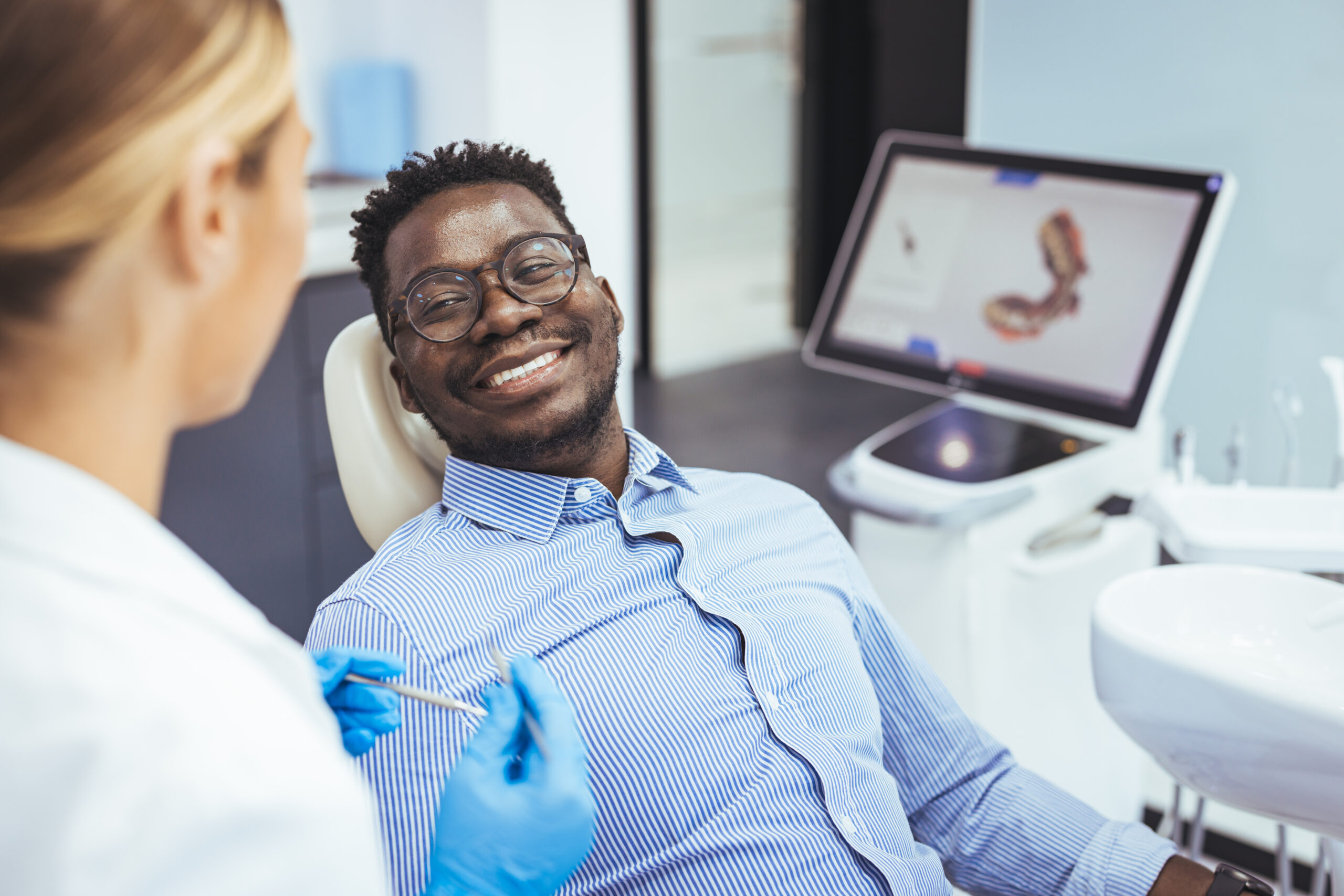 Young african-american man visiting dentist's office for prevention and treatment of the oral cavity. Man and male doctor while checkup teeth. Healthy lifestyle, healthcare and medicine concept.